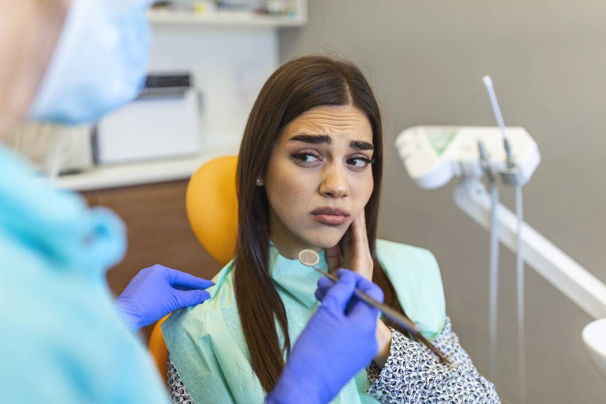 Woman at dentist with pain wondering if dental fillings can decay.
