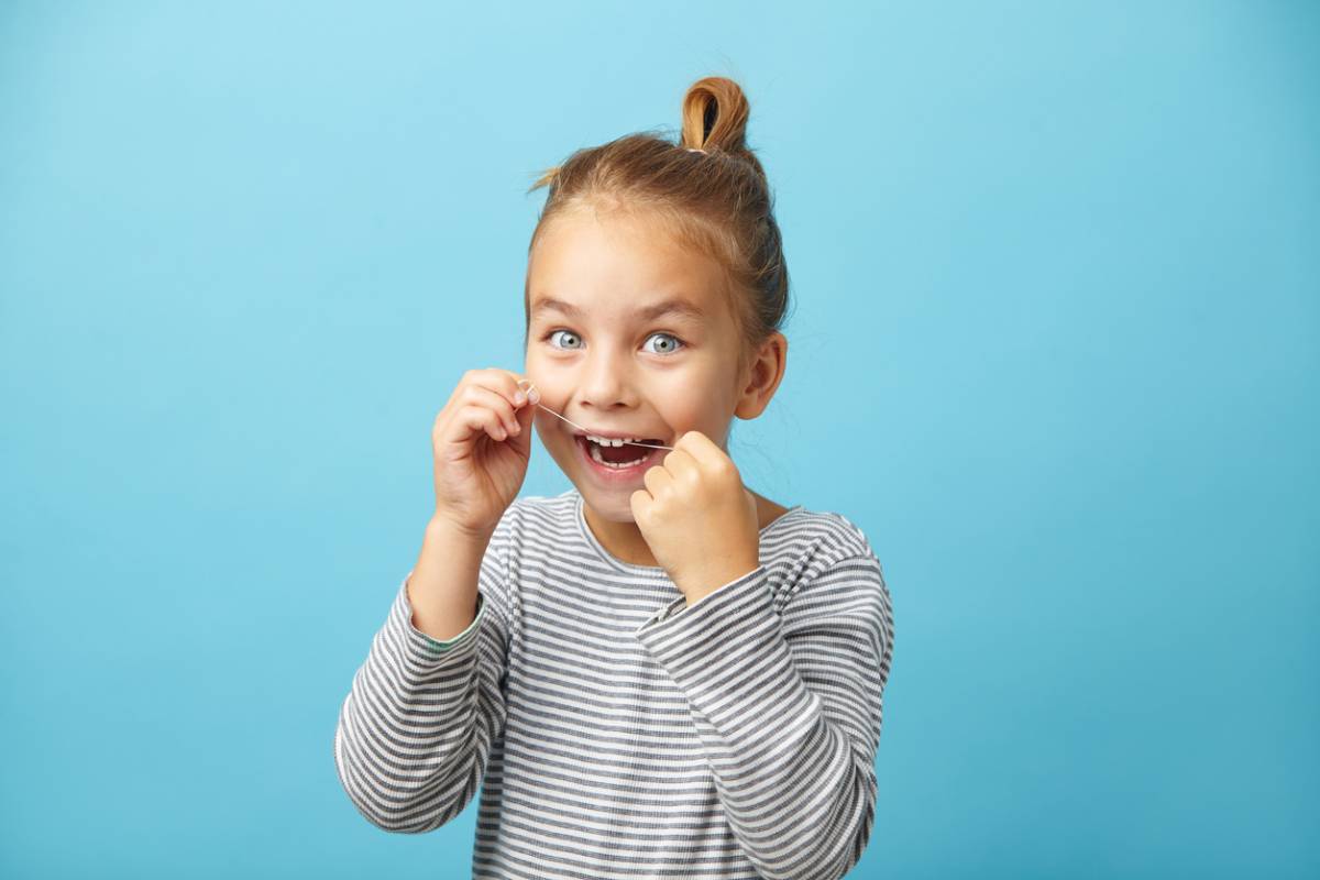 Girl flossing and starting oral hygiene young.